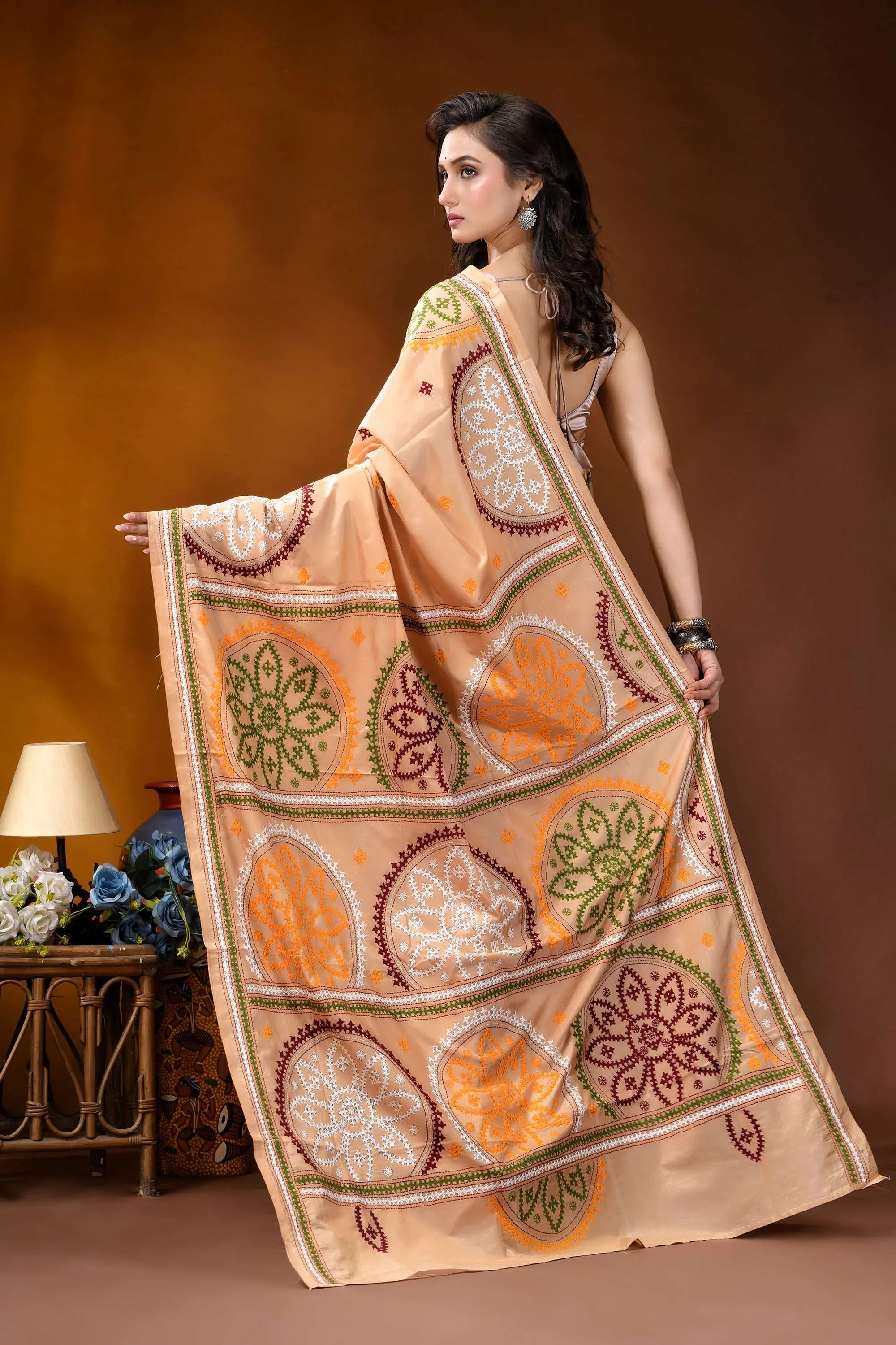 Beige multi-thread floral motif kutch embroidery silk saree woman wears peach-colored saree intricate 5